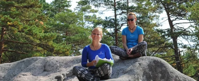 Kaks rõõmsat giidi istuvad suurel kivil ja viivad läbi meeskonnamängu.